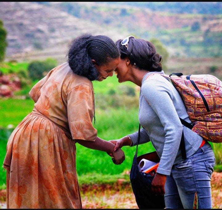 Two Tigray women greet each other with a kiss.